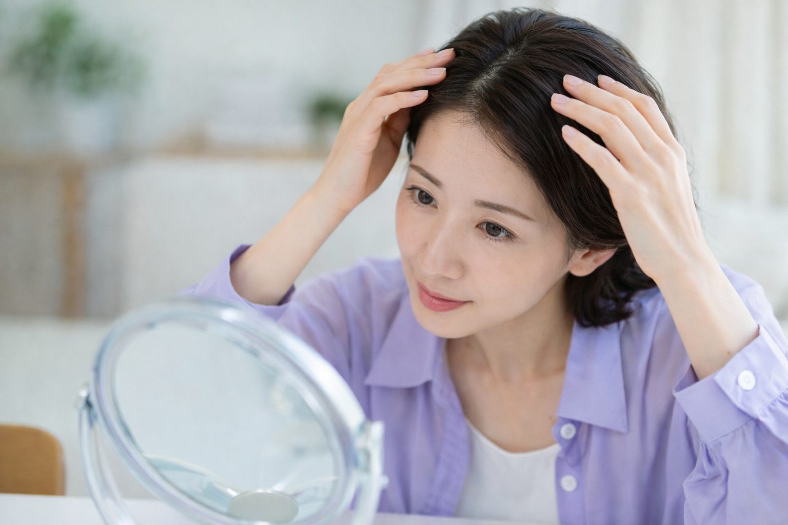鏡の前で白髪の原因と対策を意識しながら髪を確認する日本人女性